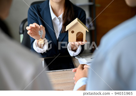 Cropped shot, An expert female real estate agent holding a house model and house key. 94031965