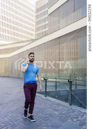 Portrait of cheerful modern businessman speaking by phone and smiling while standing outdoors 94032256