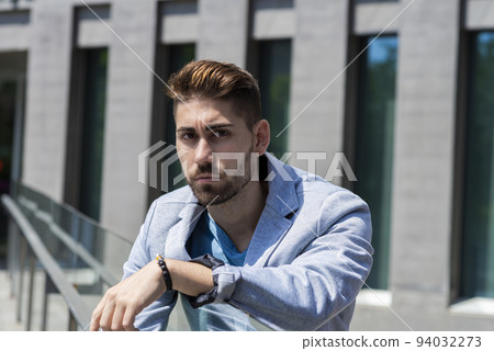 Young man leaning on railings outdoor while looking to camera Young man leaning on railings outdoor while looking to camera 94032273