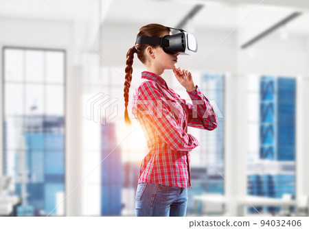 Girl in virtual reality mask experiencing virtual technology world. Mixed media 94032406