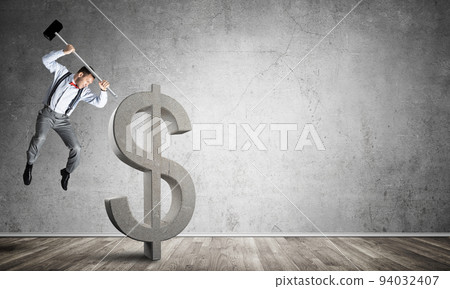 Determined banker man in empty concrete room breaking dollar figure 94032407