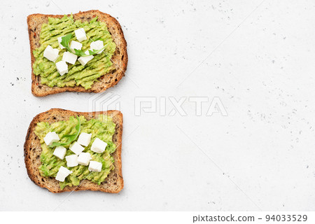 Whole grain toasted bread with mashed avocado and feta cheese 94033529