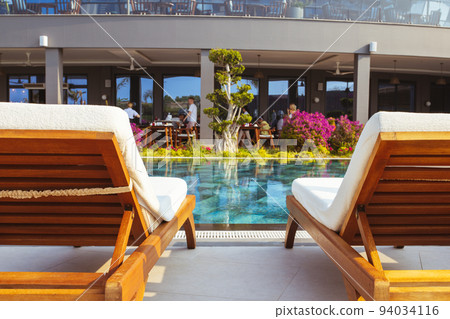 Beautiful luxury umbrella and chair around outdoor swimming pool in hotel and resort with coconut palm tree on blue sky Beautiful luxury umbrella and chair around outdoor swimming pool in hotel and resort with coconut palm tree on blue sky 94034116