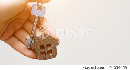 A woman's hand holds a house key on a white background with copy space. Real estate agent. Buying a house, apartment. A woman's hand holds a house key on a white background with copy space. Real estate agent. Buying a house, apartment. 94034469