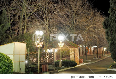 Path at night in the park of the resort. Recreation area on the territory of the resort with lampposts. 94035960