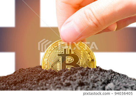 Legalization of bitcoins in Finland. Planting a Bitcoin in the ground against the background of the flag of Finland. Finland - investment in cryptocurrency.  94036405