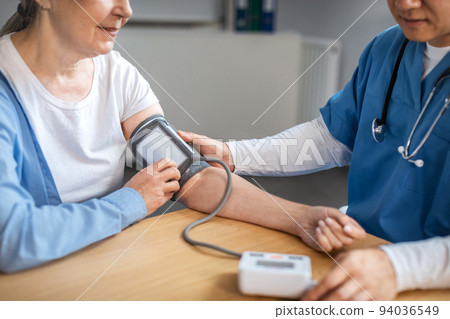 Concentrated adult asian male doctor measures pressure with tonometer to old woman patient in clinic Concentrated adult asian male doctor measures pressure with tonometer to old woman patient in clinic 94036549