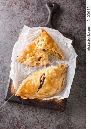 Freshly baked homemade Cornish pasties closeup on the wooden board. Vertical top view 94036594