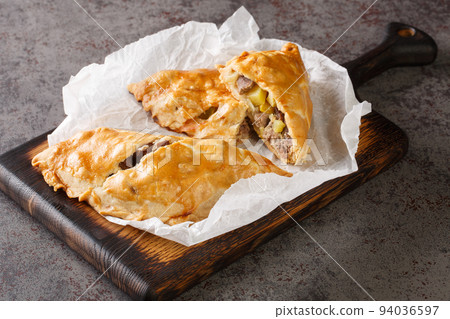 English pies Cornish pasties stuffed with beef, potatoes and swede close-up on paper. horizontal 94036597