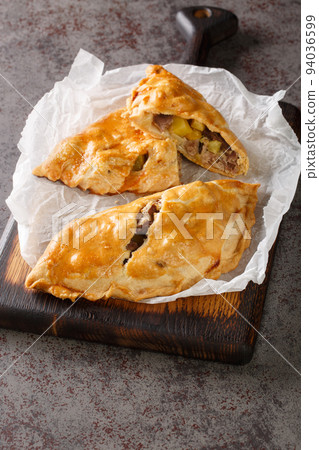 Traditional Cornish pasty filled with meat potato swede and carrot closeup on the paper. Vertical 94036599