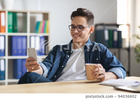 Young Male Office Employee Relaxing With Smartphone And Coffee At Workplace, 94036602