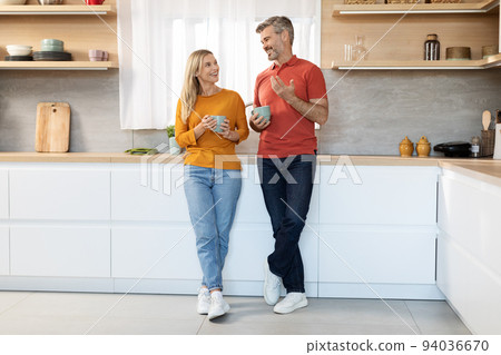 Cheerful married couple having conversation while drinking tea Cheerful married couple having conversation while drinking tea 94036670