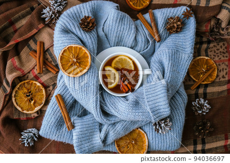 Blue sweater and cup of hot tea with lemon cinnamon sticks and anise star. Dry slices of citrus orange and cones. Hot winter cocktail. Christmas, Thanksgiving drinks. Autumn, grog, hot sangria, mulled Blue sweater and cup of hot tea with lemon cinnamon sticks and anise star. Dry slices of citrus orange and cones. Hot winter cocktail. Christmas, Thanksgiving drinks. Autumn, grog, hot sangria, mulled 94036697