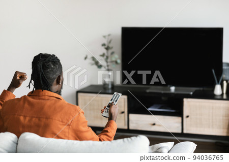 African american man cheerfing for favourite team, watching sports game on TV, television set with empty screen 94036765