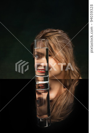 Split. Modern art photography. Beautiful girl's face through glass of water. Object distortion, optical illusion. Minimalistic contemporary art. 94039328