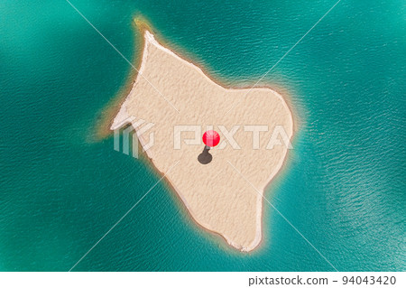 Woman with red rain umbrella walking on a small uninhabited, desert sand island in the middle of sea. Drone view, aerial view, top view 94043420