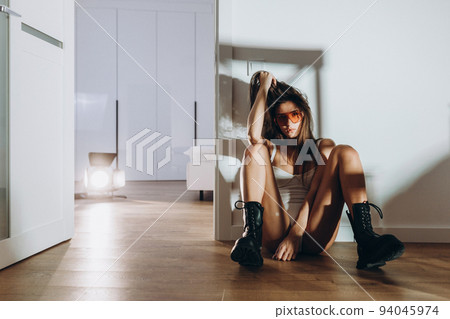 A young beautiful model woman is standing, posing in the kitchen in, white underwear. The girl has long dark hair, full lips and a beautiful face. Tanned, athletic, skinny body in the bodysuit. A young beautiful model woman is standing, posing in the kitchen in, white underwear. The girl has long dark hair, full lips and a beautiful face. Tanned, athletic, skinny body in the bodysuit. 94045974