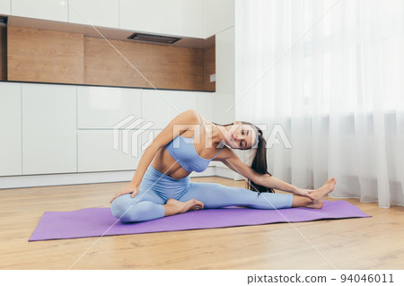 Sports time. Young beautiful fitness woman doing exercises at home on the mat, lifts her legs, shakes the press, squeezes Sports time. Young beautiful fitness woman doing exercises at home on the mat, lifts her legs, shakes the press, squeezes 94046011