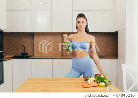 Young beautiful fitness woman preparing detox drink with fresh fruits, mint and lemon at home in the kitchen Young beautiful fitness woman preparing detox drink with fresh fruits, mint and lemon at home in the kitchen 94046210