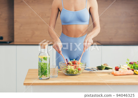 Close up photo, body part, hands of young fitness woman making salad with fresh vegetables and fresh detox drink in kitchen at home Close up photo, body part, hands of young fitness woman making salad with fresh vegetables and fresh detox drink in kitchen at home 94046325