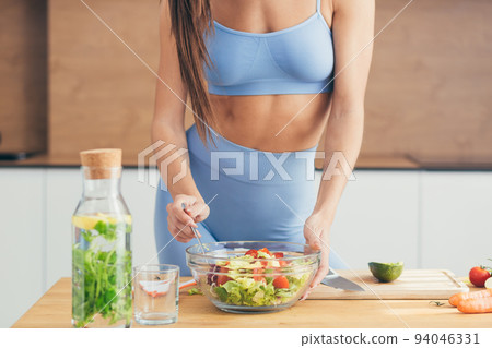 Close up photo, body part, hands of young fitness woman making salad with fresh vegetables and fresh detox drink in kitchen at home Close up photo, body part, hands of young fitness woman making salad with fresh vegetables and fresh detox drink in kitchen at home 94046331