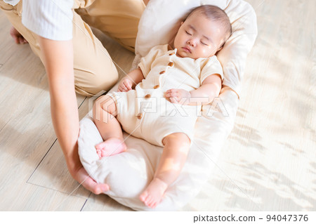 A mother who gently puts down the baby so that it doesn't wake up. A mother who gently puts down the baby so that it doesn't wake up. 94047376