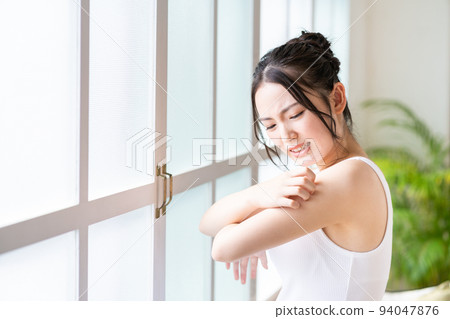 Young woman scratching her arm. 94047876