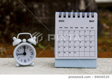 Alarm clock pointing at 9 o'clock with May 2023 calendar. Time and calendar concept 94048520