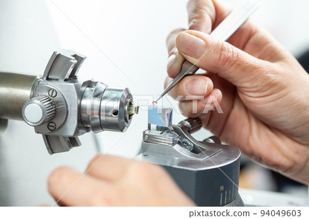 Closeup of a female scientist placing a sample on a transmission electron microscopy grid 94049603