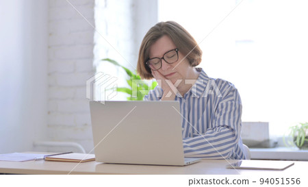 Senior Woman Sleeping While Sitting in Office with Laptop Senior Woman Sleeping While Sitting in Office with Laptop 94051556