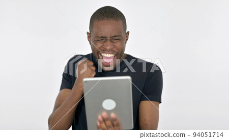 Young African Man Celebrating Success on Tablet on White Background Young African Man Celebrating Success on Tablet on White Background 94051714
