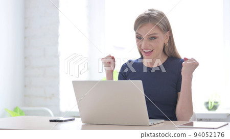 Woman Celebrating Online Success in Office Woman Celebrating Online Success in Office 94052176