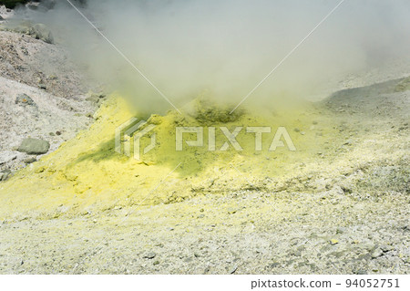 yellow cone of crystallized sulfur around a smoking solfatara on the slope of a volcano 94052751