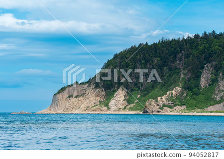 coastal seascape, beautiful lava rocks on the wooded coast of Kunashir island near Cape Stolbchaty coastal seascape, beautiful lava rocks on the wooded coast of Kunashir island near Cape Stolbchaty 94052817