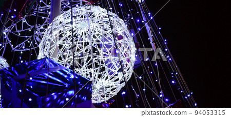 Fragment of the New Year tree. A lot of round lights of blue color are located on a conical frame 94053315