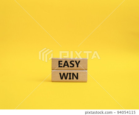 Easy win symbol. Wooden blocks with words 'Easy win'. Beautiful yellow background. Business and 'Easy win' concept. Copy space. Easy win symbol. Wooden blocks with words 'Easy win'. Beautiful yellow background. Business and 'Easy win' concept. Copy space. 94054115