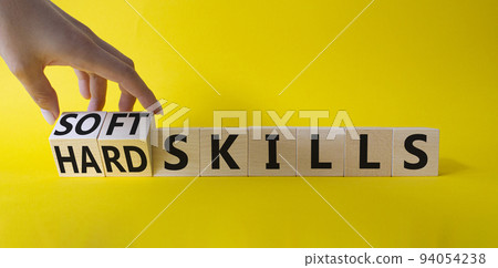 Soft Skills and Hard Skills symbol. Hand turns a cube and changes the words Soft Skills to Hard Skills. Beautiful yellow background. Businessman hand. Business concept. Copy space 94054238