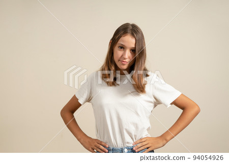 Cute spanish girl with brunette hair looking at camera with arms akimbo, isolated on beige background 94054926