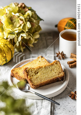 Two slices of pumpkin bread on white plate with pumpkins and seasonal flowers hydrangea on gray background. Autumn dessert 94054931