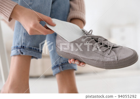 Woman putting orthopedic insole into shoe at home, closeup Woman putting orthopedic insole into shoe at home, closeup 94055292