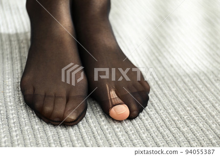 Woman wearing torn tights at home, closeup Woman wearing torn tights at home, closeup 94055387
