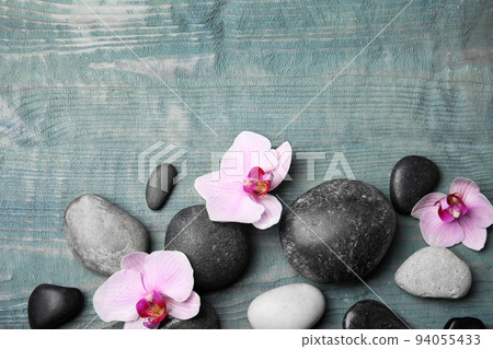 Stones with orchid flowers and space for text on blue wooden background, flat lay. Zen lifestyle 94055433