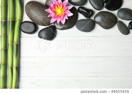 Stones, bamboo, lotus flower and space for text on white wooden background, flat lay. Zen lifestyle Stones, bamboo, lotus flower and space for text on white wooden background, flat lay. Zen lifestyle 94055439