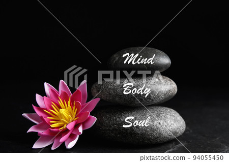 Stones with words Mind, Body, Soul and lotus flower on black background. Zen lifestyle Stones with words Mind, Body, Soul and lotus flower on black background. Zen lifestyle 94055450