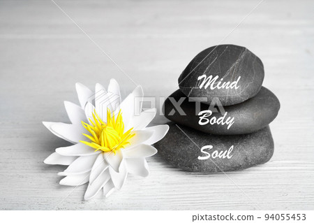 Stones with words Mind, Body, Soul and lotus flower on white wooden table. Zen lifestyle 94055453
