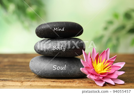 Stones with words Mind, Body, Soul and lotus flower on wooden table. Zen lifestyle Stones with words Mind, Body, Soul and lotus flower on wooden table. Zen lifestyle 94055457