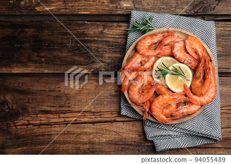 Delicious cooked shrimps with rosemary and lemon on wooden table, top view. Space for text 94055489