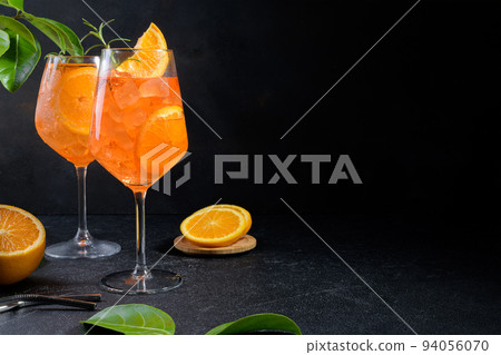 Classic italian aperitif aperol spritz cocktail in two glass with ice, slice of orange on black background 94056070