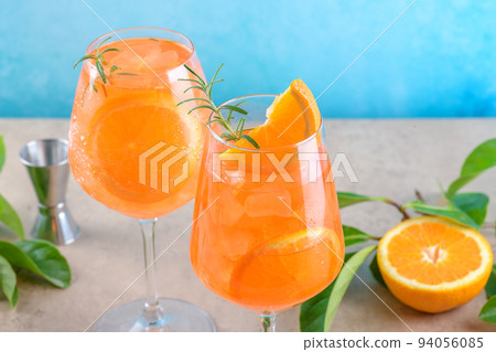 Classic italian aperitif aperol spritz cocktail in two glass with ice, orange on blue background on marble podium 94056085