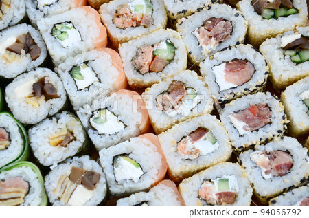 Close-up of a lot of sushi rolls with different fillings. Macro shot of cooked classic Japanese food. Background image 94056792